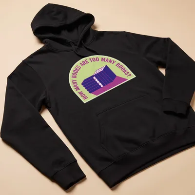 Bold typography t-shirt with humorous text about book collecting over a stack of books — printed on a unisex hoodie