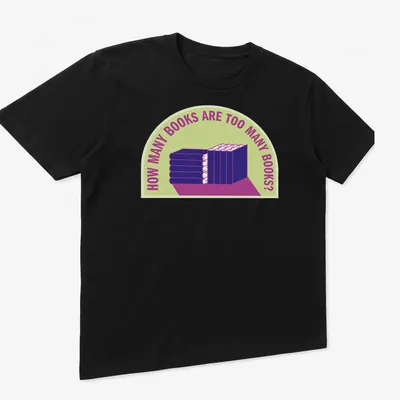 Bold typography t-shirt with humorous text about book collecting over a stack of books — printed on a unisex t-shirt (angled view)
