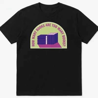 Bold typography t-shirt with humorous text about book collecting over a stack of books