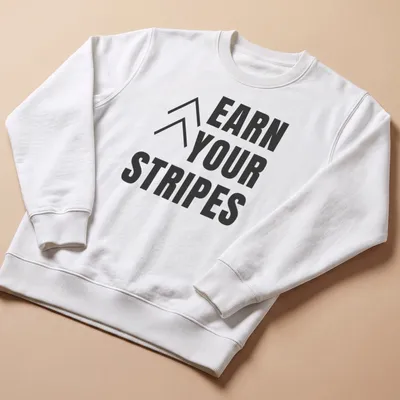 Bold typography t-shirt with the message 'Earn Your Stripes' in black and white. — printed on a unisex sweatshirt
