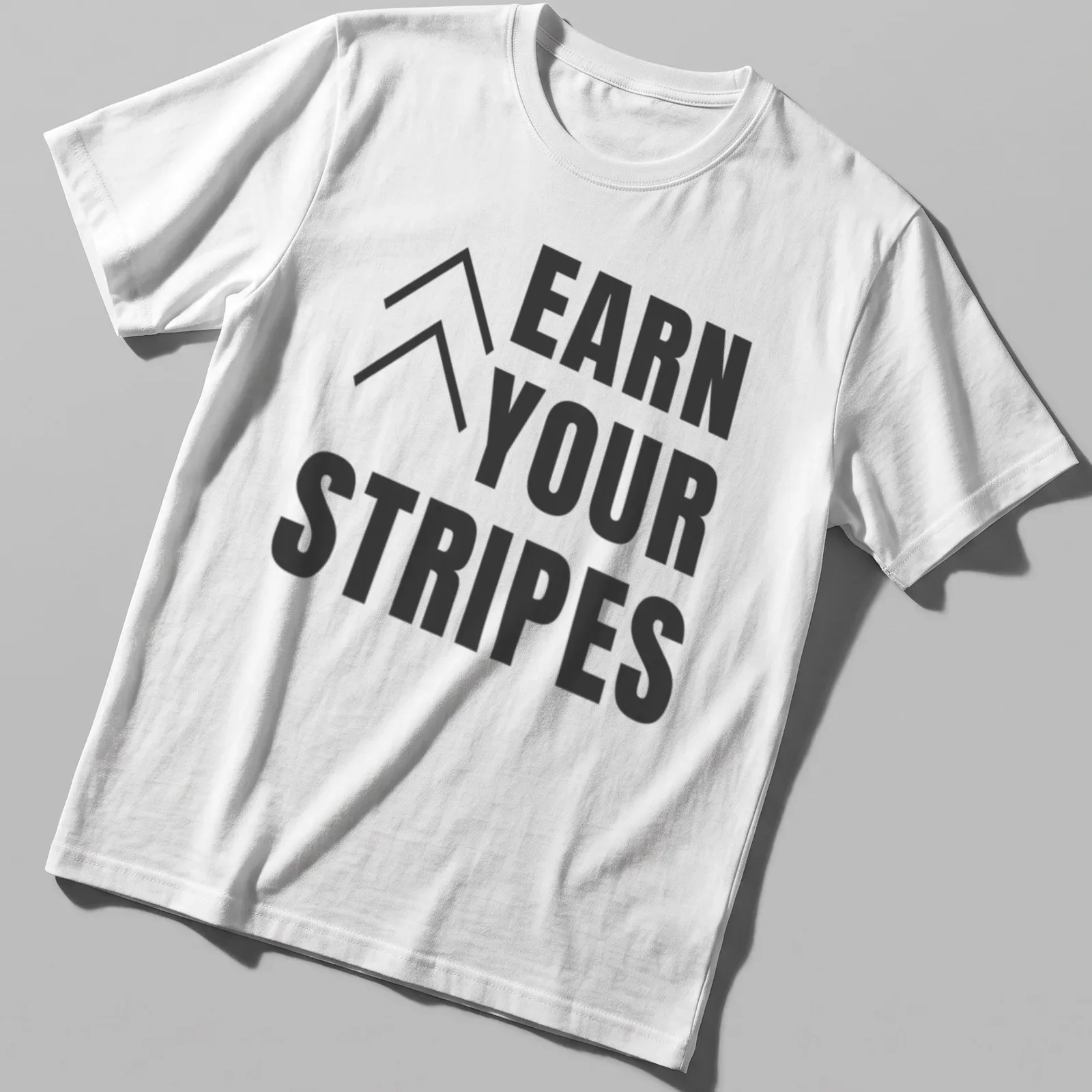 Bold typography t-shirt with the message 'Earn Your Stripes' in black and white. — printed on a unisex t-shirt