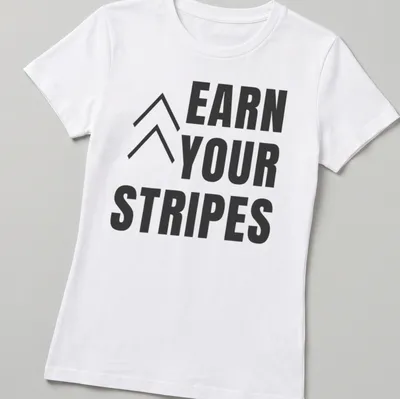 Bold typography t-shirt with the message 'Earn Your Stripes' in black and white. — printed on a women's shirt