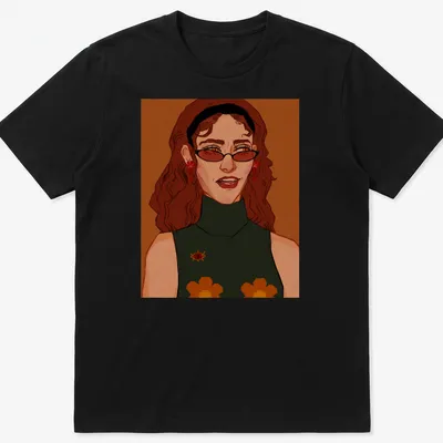 Illustrative T-shirt featuring a woman with glasses and floral accessories in warm colors.