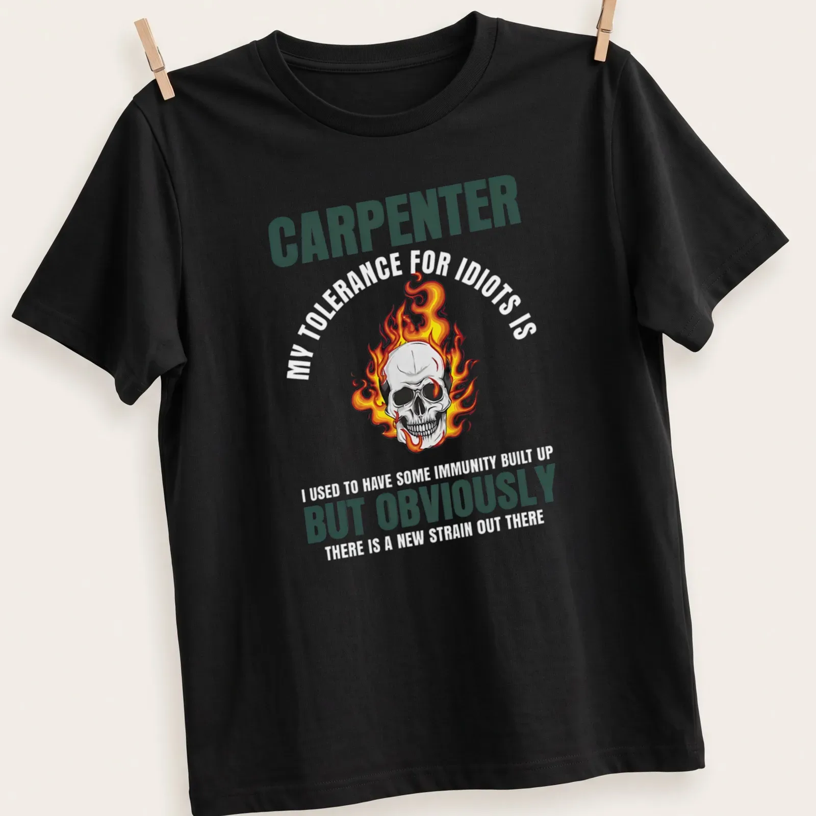 Bold graphic of a flaming skull with text 'CARPENTER BUT OBVIOUSLY' in black and orange — printed on a unisex t-shirt