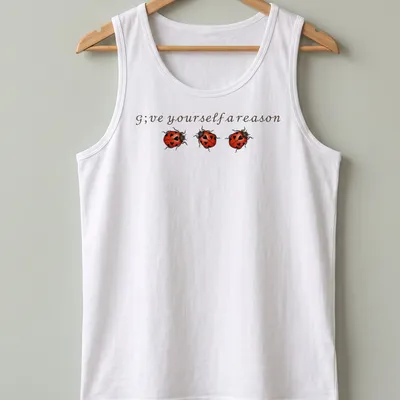 Whimsical ladybug illustration above the text 'G;ve yourself a reason' in red, black, and brown. — printed on a tank top