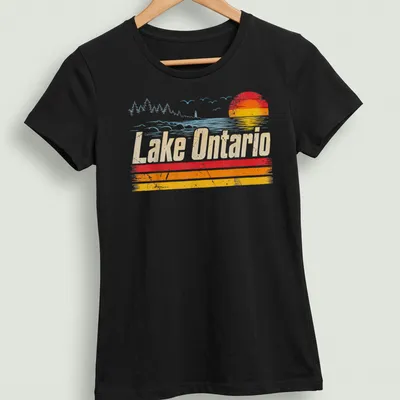 Retro distressed Lake Ontario T-shirt featuring sunset colors in orange, yellow, light blue, and white — printed on a women's shirt