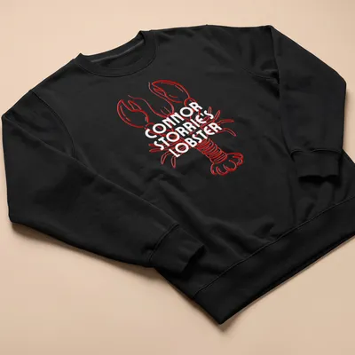 Line-art lobster illustration in red on a T-shirt resembling a magazine cover — printed on a unisex sweatshirt