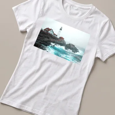 Photographic print of a lighthouse enduring ocean storm waves in blue and gray — printed on a women's shirt