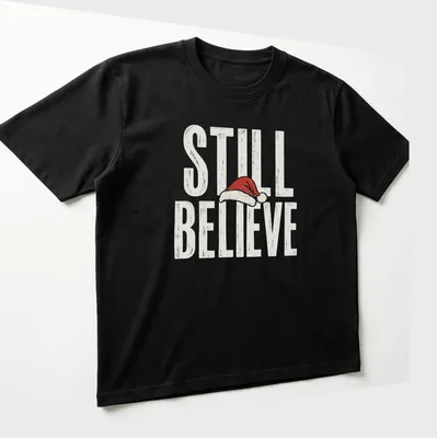 Vintage distressed t-shirt featuring a Santa hat and the phrase 'Still Believe' in bold letters. — printed on a unisex t-shirt (angled view)