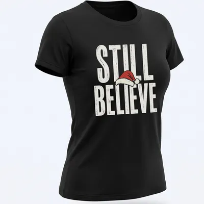 Vintage distressed t-shirt featuring a Santa hat and the phrase 'Still Believe' in bold letters. — printed on a women's shirt