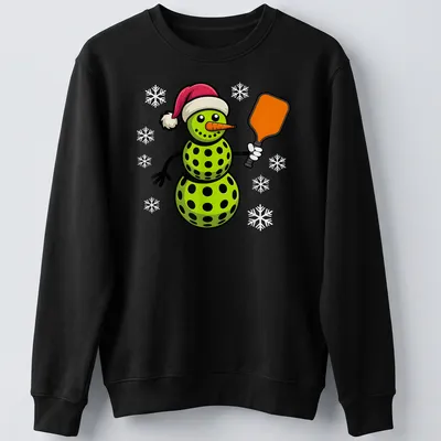 Cartoon snowman playing pickleball in red and green with festive colors — printed on a unisex sweatshirt