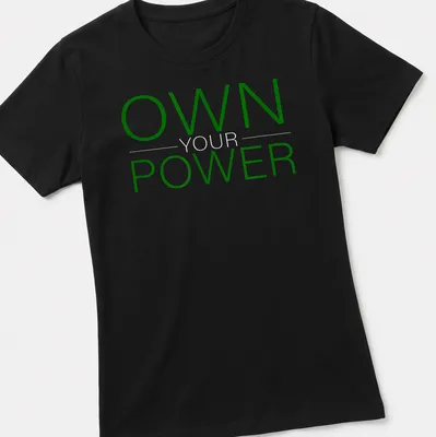 Bold typography shirt with 'OWN YOUR POWER' in dark green and white — printed on a women's shirt